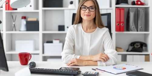 A young girl is sitting at the computer desk in the office. A young girl is sitting at the computer desk in the office.